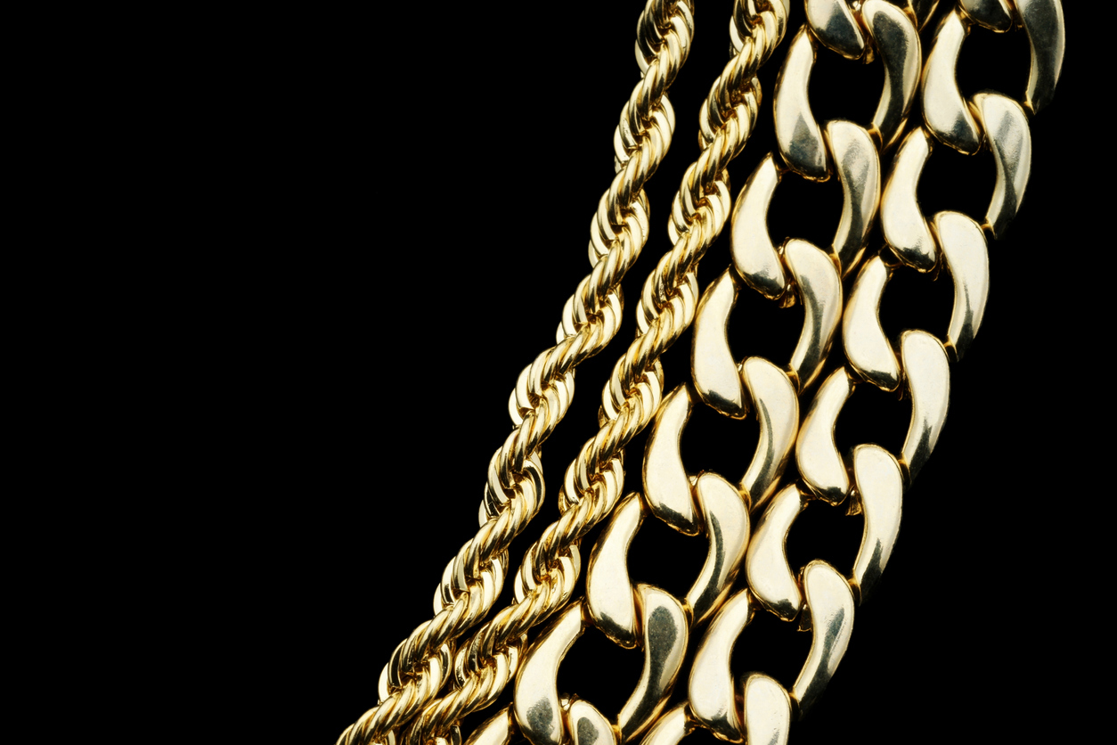 Gold chain necklaces with different link designs on a black background.