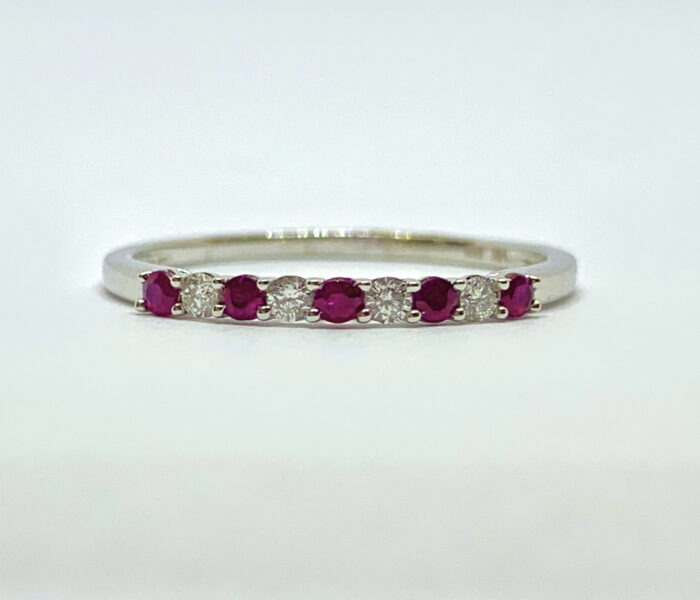 Silver ring with a row of pink gems and small diamonds.
