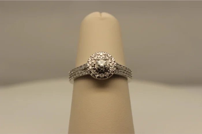 A close-up of a diamond ring displayed on a beige ring stand.
