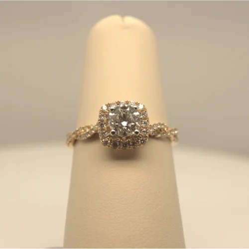 A close-up of a cushion cut diamond engagement ring on a beige ring display.