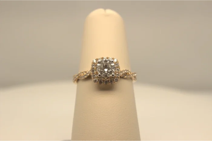 A close-up of a cushion cut diamond engagement ring on a beige ring display.
