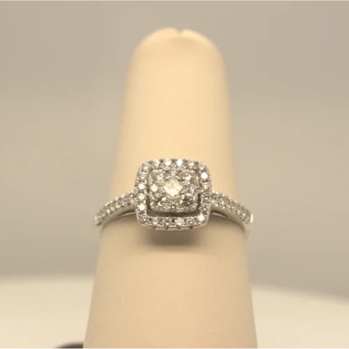 A diamond engagement ring with a cushion halo setting on a cream ring stand.