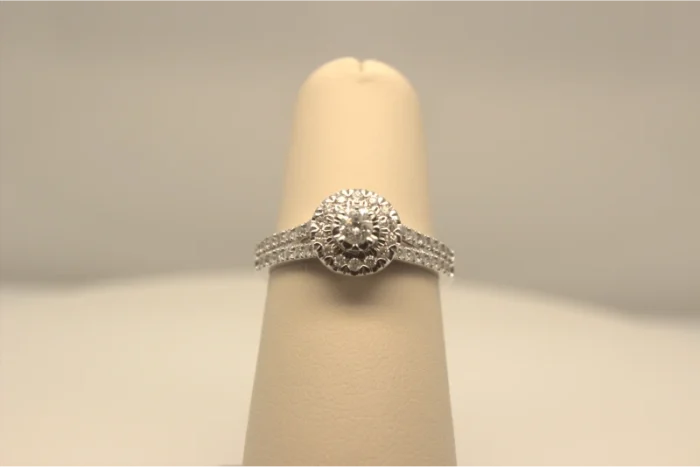An elegant diamond engagement ring presented on a cream-colored ring display.